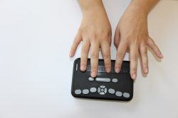 View of the top of the Reader with two hands on the braille keys