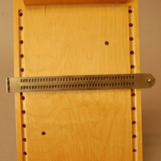 Une planche en bois avec des trous de guidage de chaque côté et une tablette en métal.